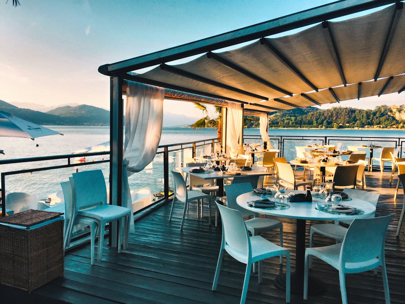 A set restaurant table on a wooden terrace overlooking the sea at golden hour — the per-cover revenue these consultations examine.